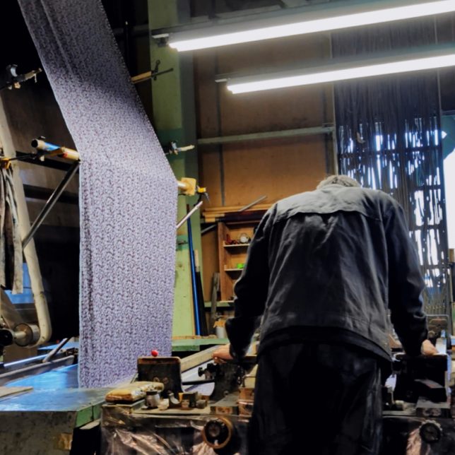 プリント機にセットされたリバティ柄のリネン生地、何度もテストを重ね自然なリネンに再現する調整の工場風景